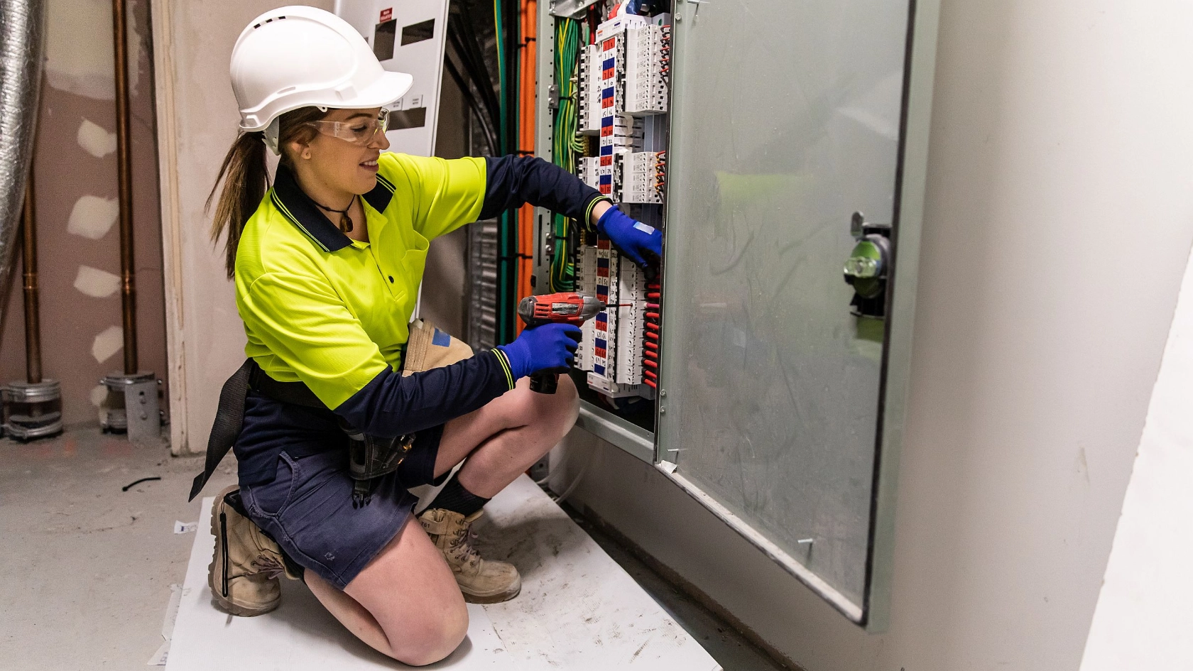 Elektrohandwerkerin arbeitet am Verteilerkasten