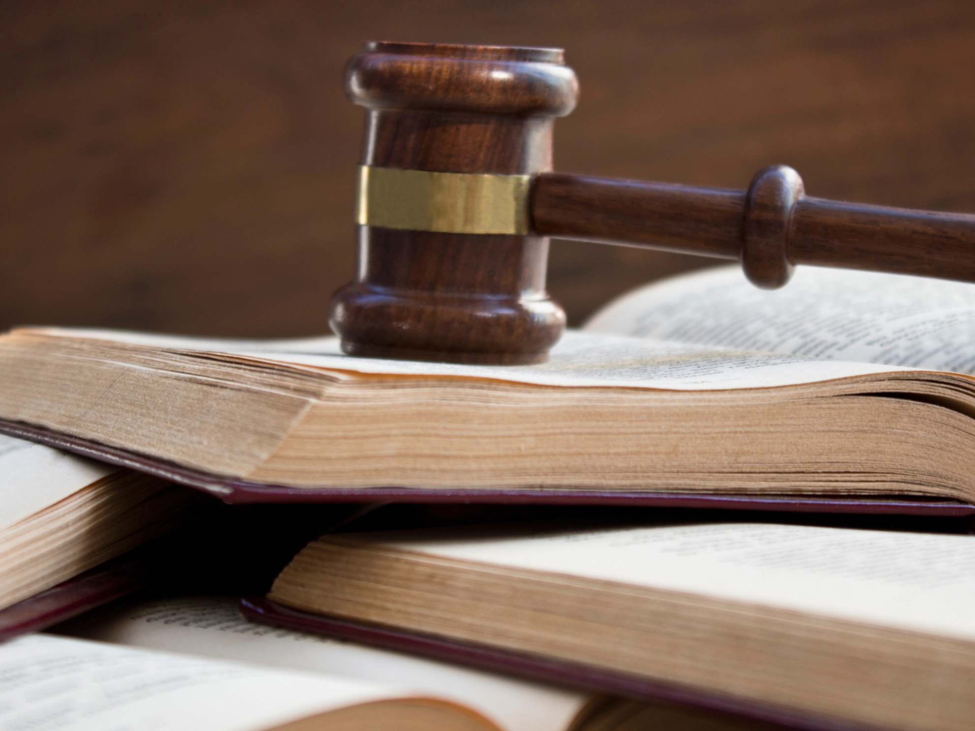 Ein Richterhammer liegt auf geöffnetem Gesetzbuch, mehrere Gesetzbücher liegen darunter